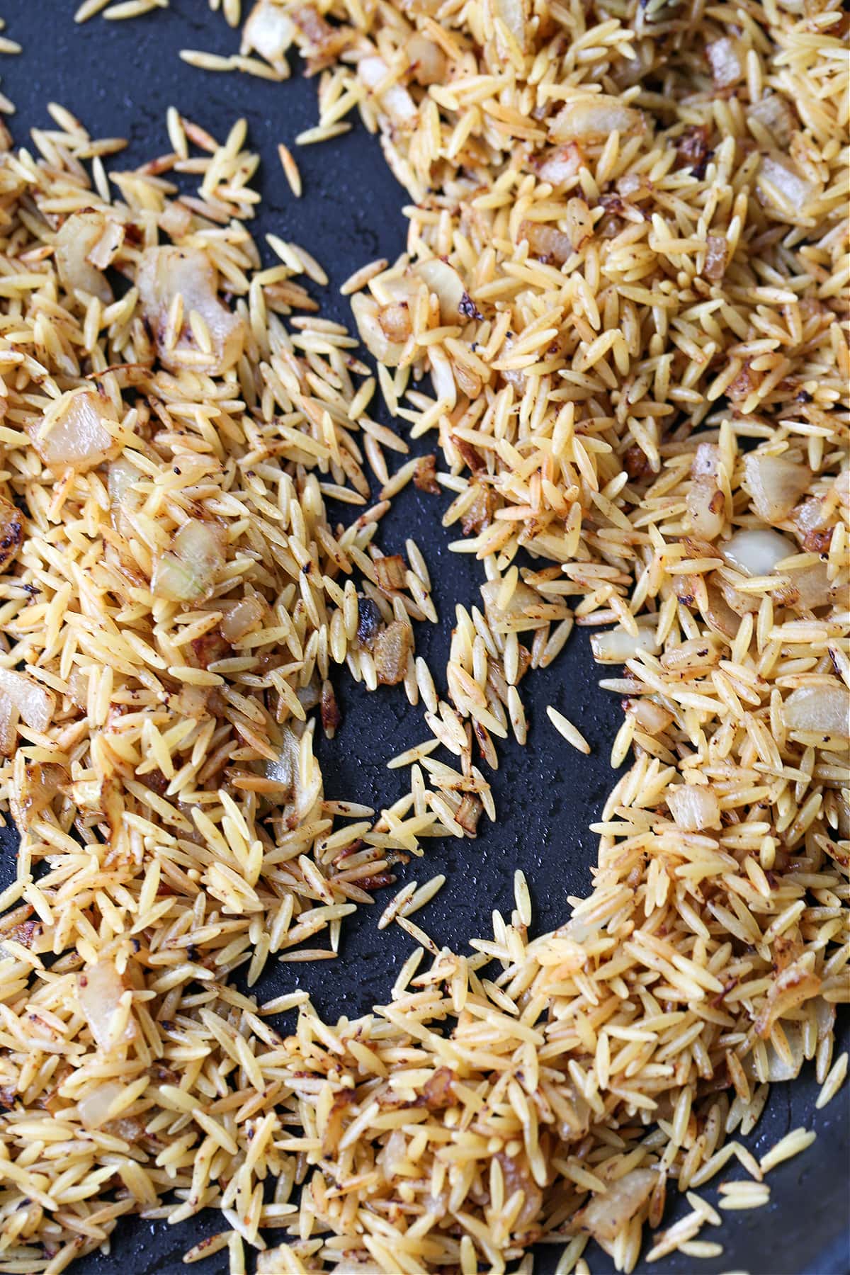 orzo and onion browned in a skillet