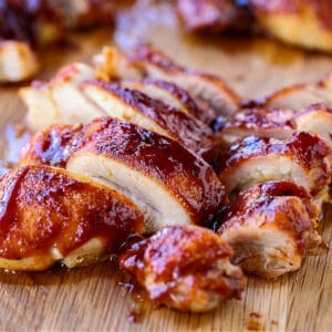 BBQ boneless chicken thighs sliced on a cutting board