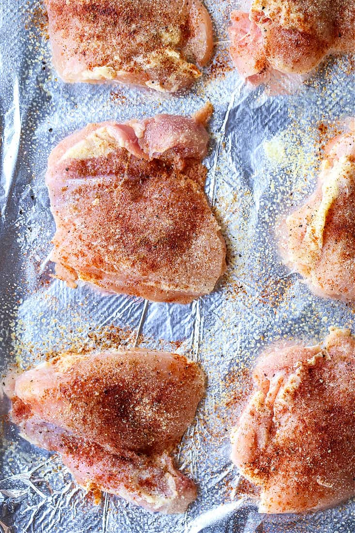 boneless, skinless chicken thighs on a sheet pan with seasoning