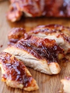 barbecure boneless chicken thighs sliced on a board
