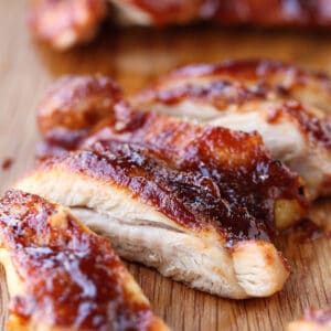 barbecure boneless chicken thighs sliced on a board