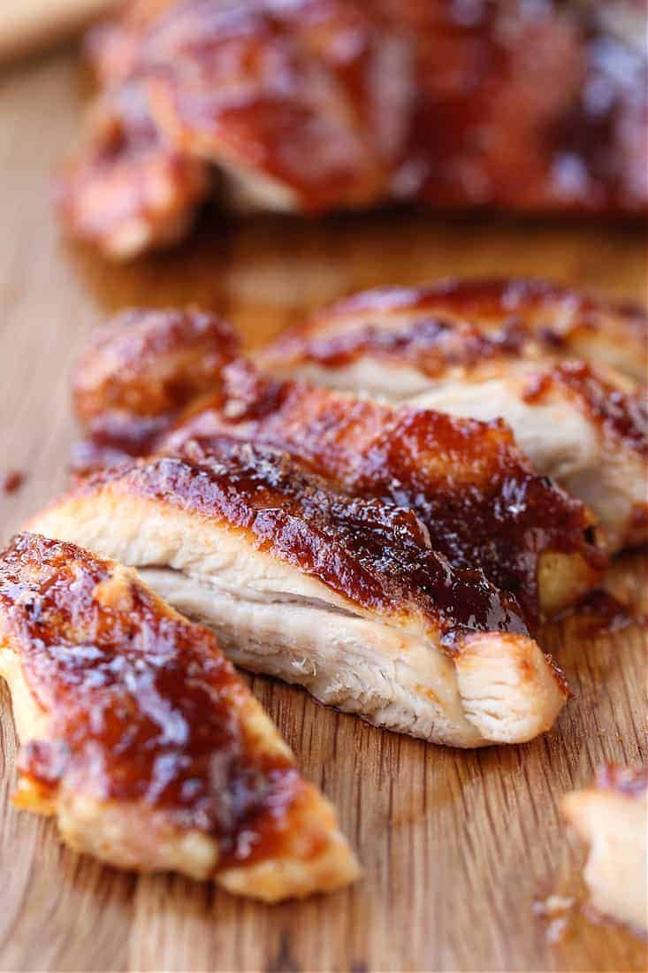 barbecure boneless chicken thighs sliced on a board