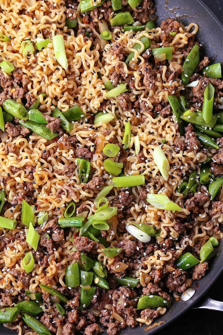 Ground beef and ramen noodles in a skillet with peas