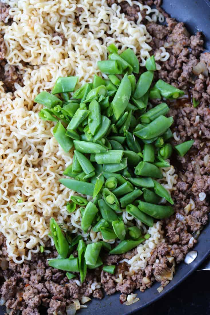 Sugar snap peas with ramen noodles and ground beef in a skillet