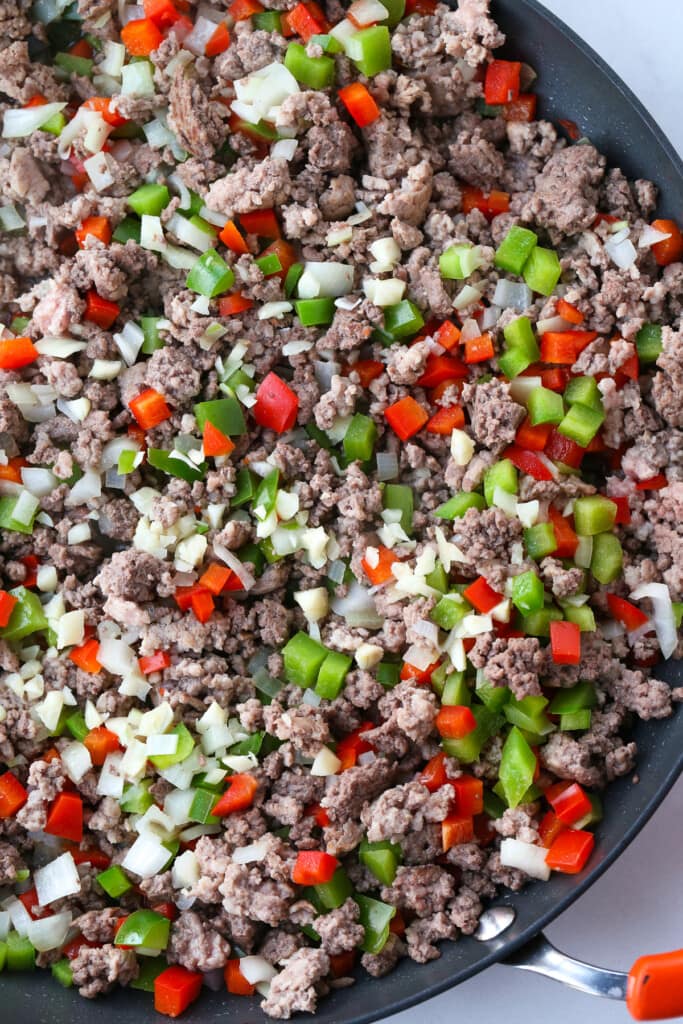 Italian Sloppy Joes are an easy dinner recipe that everyone loves! An Italian twist to a sloppy joe with peppers, onions and melted cheese! ground beef, peppers and onions in a skillet