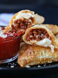 Puff Pastry Pizza Pockets cut in half on a plate with sauce