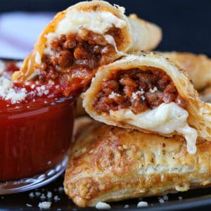 Puff Pastry Pizza Pockets cut in half on a plate with sauce