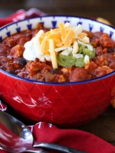 Chicken chili recipe in red bowl with cheese on top
