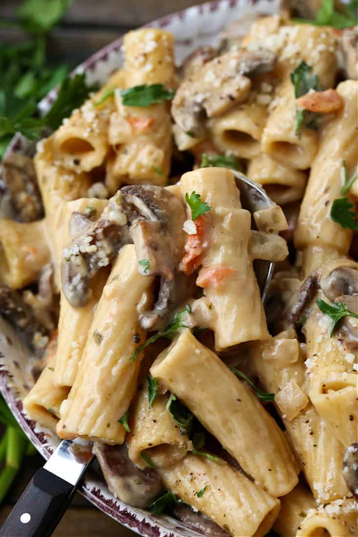 Pasta with mushrooms in a bowl with a serving spoon