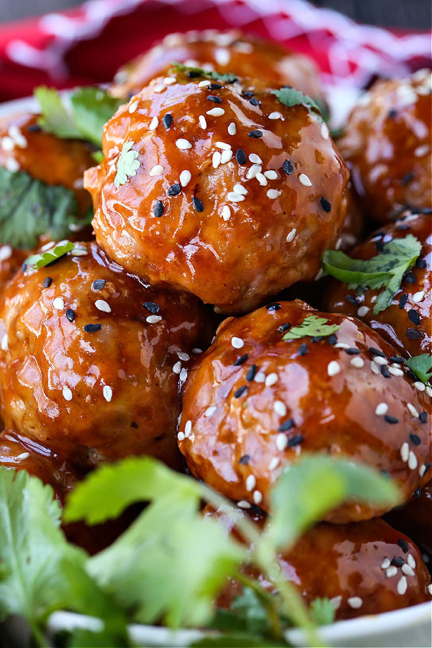 This Teriyaki Meatball recipe is one of our favorite, easy to make dinners! Oven baked, flavorful meatballs tossed in a teriyaki glaze! A Teriyaki Meatball recipe in a bowl with sesame seeds and cilantro