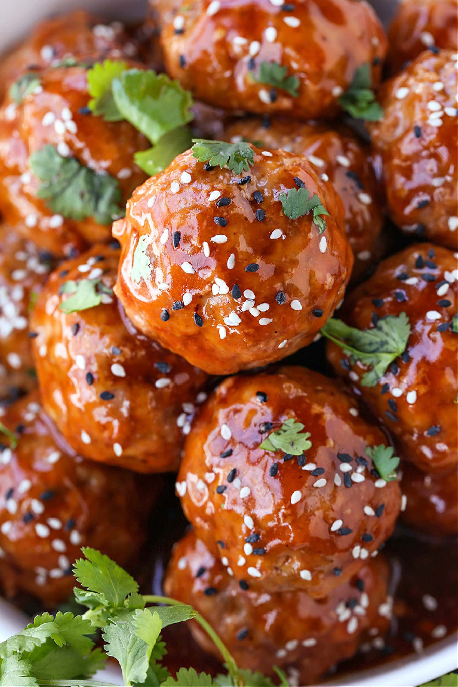 This Teriyaki Meatball recipe is one of our favorite, easy to make dinners! Oven baked, flavorful meatballs tossed in a teriyaki glaze! Teriyaki Meatballs with sesame seeds and cilantro