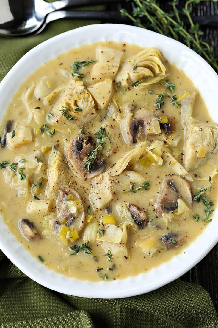 Artichoke and parsnip soup in a bowl with green napkin