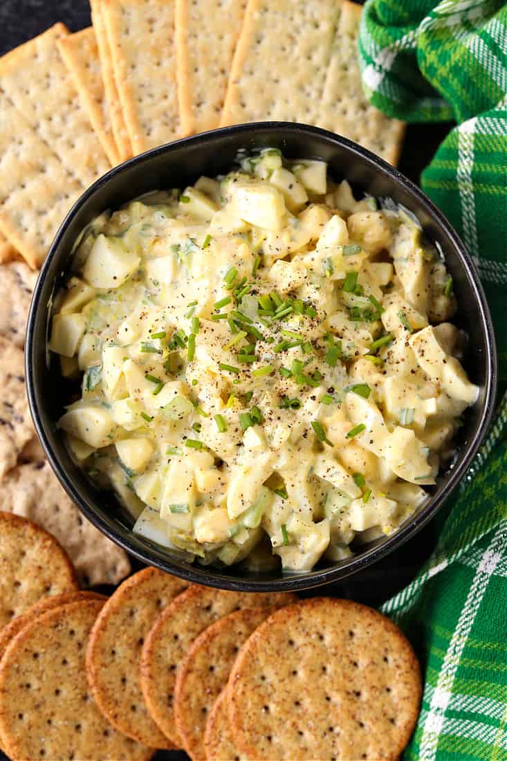 Egg salad in a black bowl with crackers