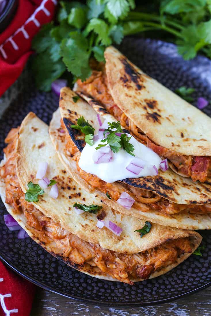Air Fryer Tacos on a black plate with sour cream and onions