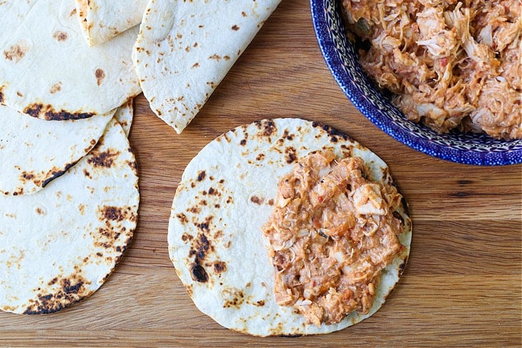 Charred tortillas on a board with chicken filling to make tacos