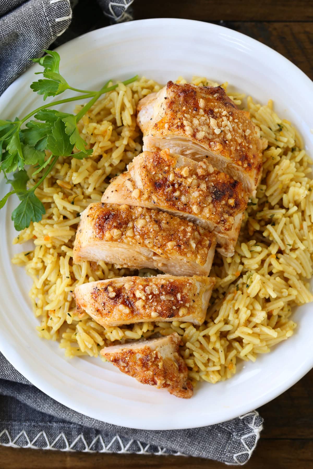Baked Parmesan Crusted Chicken is an easy, 30 minute dinner recipe! Juicy chicken breasts baked with a tangy, parmesan crust! sliced chicken breast on bed of rice pilaf