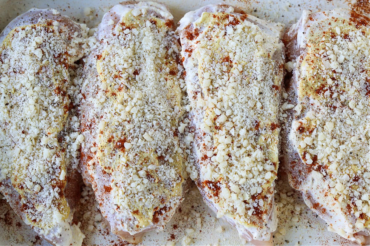 Baked Parmesan Crusted Chicken is an easy, 30 minute dinner recipe! Juicy chicken breasts baked with a tangy, parmesan crust! chicken breasts in baking dish with mayonnaise and parmesan cheese