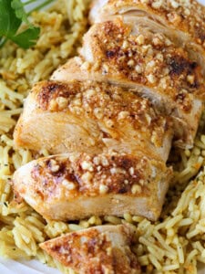 sliced parmesan crusted chicken breast on bed of rice pilaf