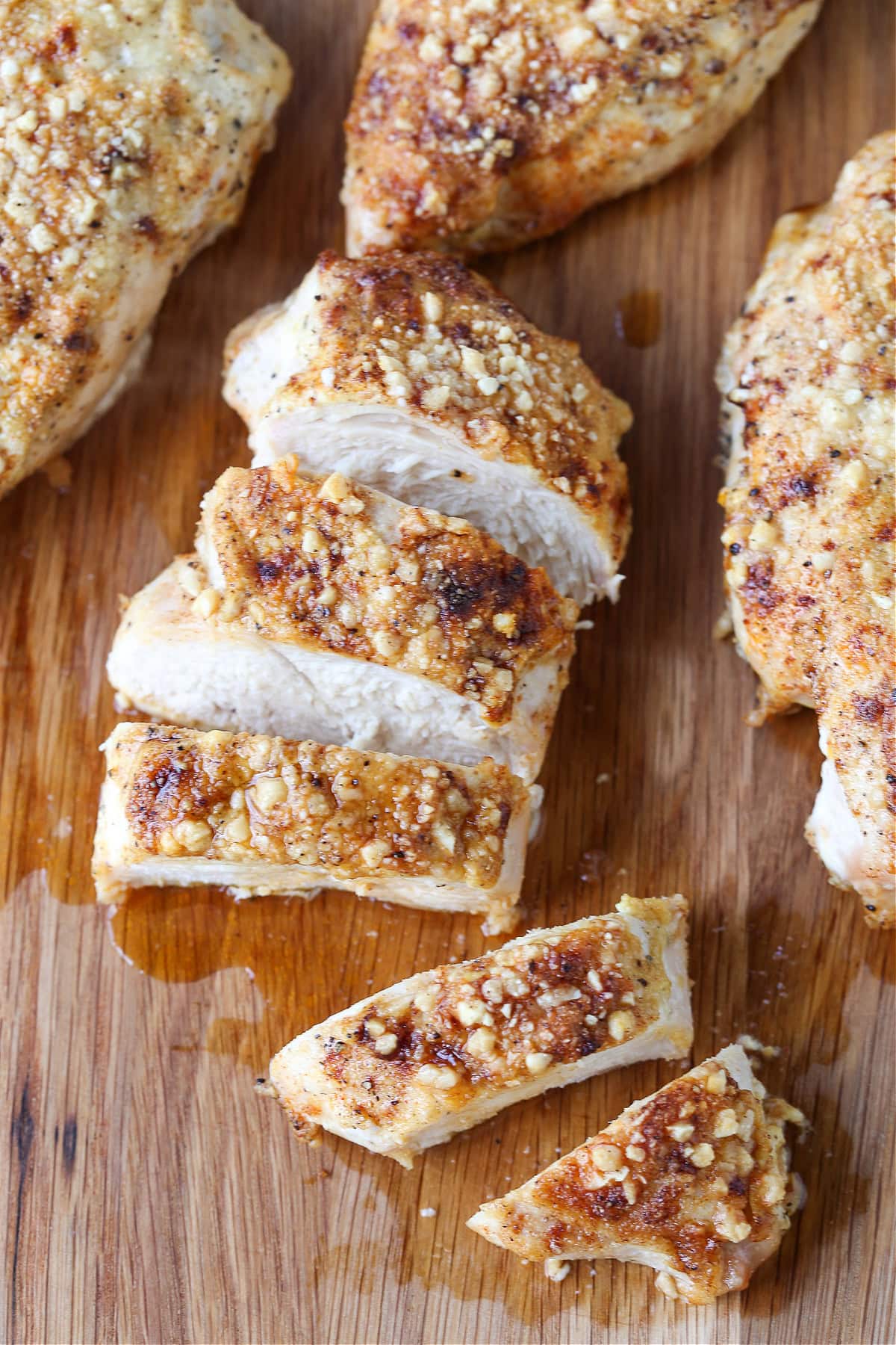 Baked Parmesan Crusted Chicken is an easy, 30 minute dinner recipe! Juicy chicken breasts baked with a tangy, parmesan crust! sliced parmesan chicken in board shown from the top