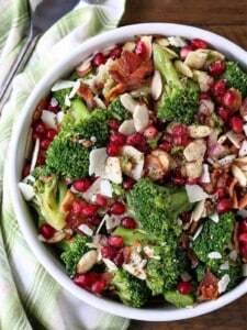 Top view of broccoli salad in a white bowl next to a cloth napkin.