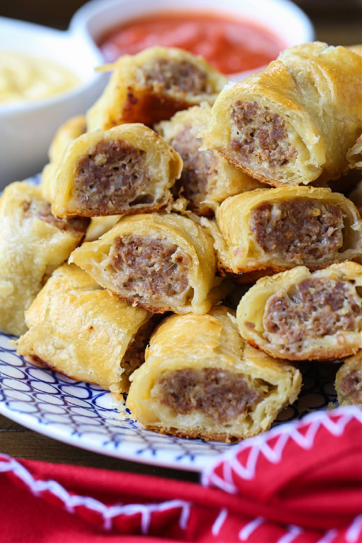 Everyone loves Puff Pastry Sausage Rolls! A buttery, flaky crust with a cheesy sausage filling. Perfect for holidays, parties and game days! puff pastry sausage rolls stacked on plate