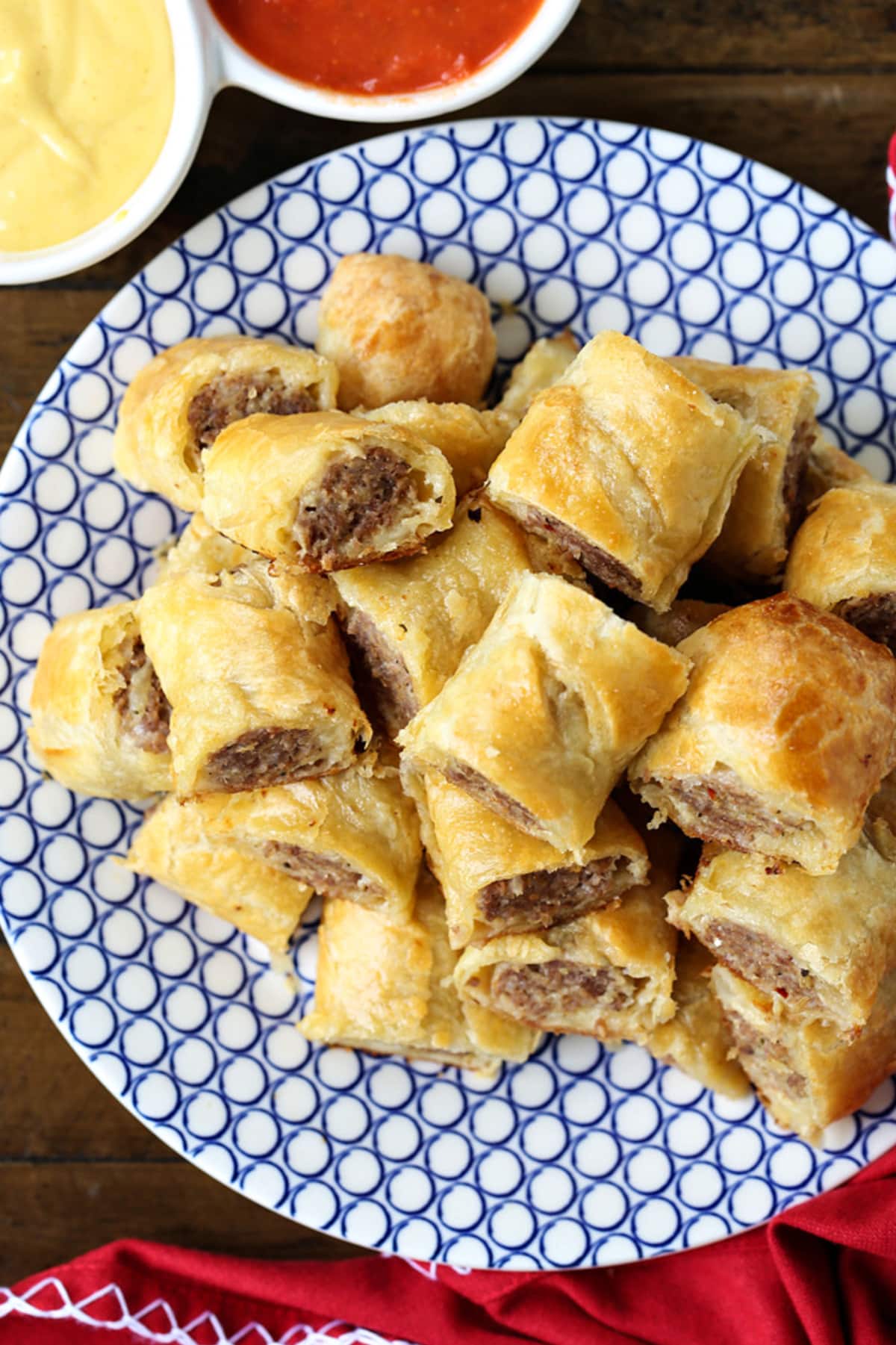 sausage rolls stacked on plate with ketchup and mustard