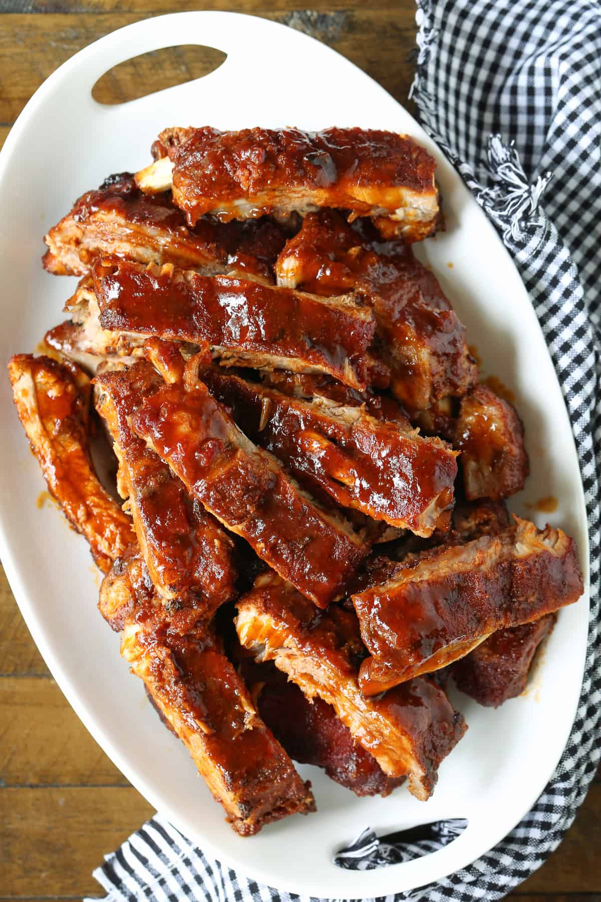 Slow Cooker BBQ Ribs couldn't be easier to make and you won't believe how amazing they turn out! An easy dinner recipe for any occasion! bbq ribs stacked on platter with napkin