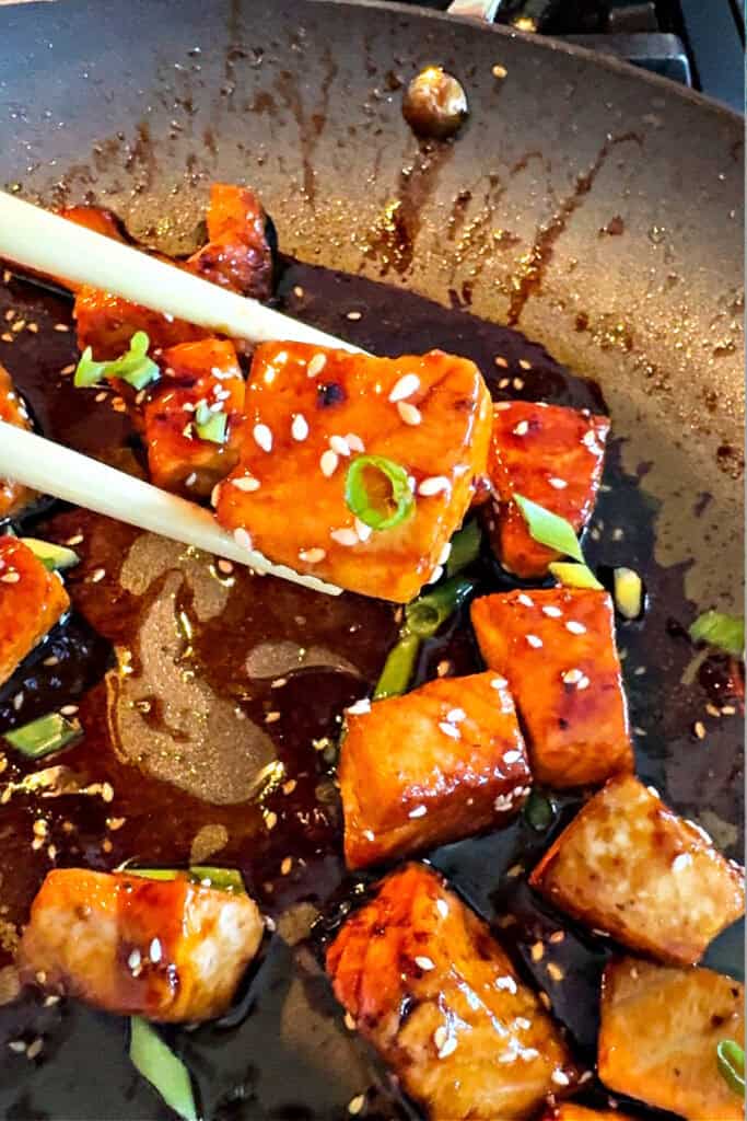 salmon bites in skillet with sesame seeds and scallions