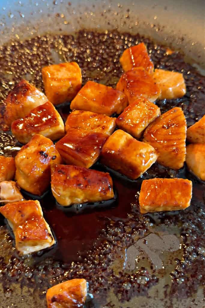 cubed salmon in a skillet with sauce