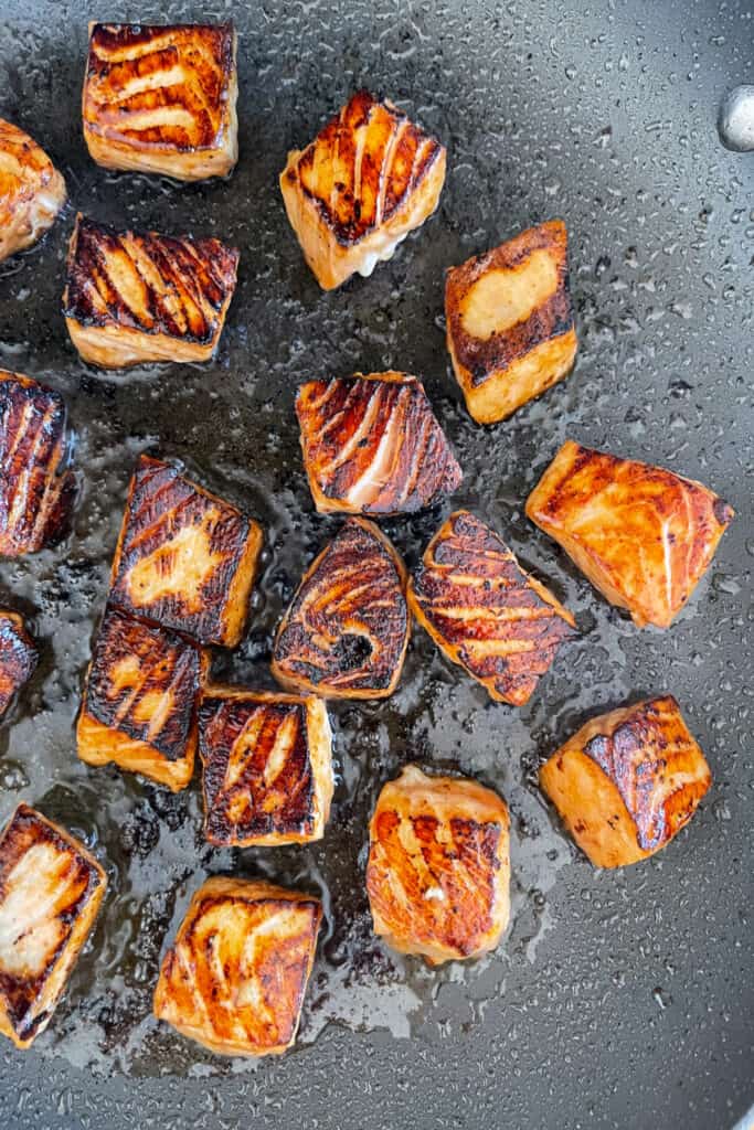 seared cubed salmon in a skillet