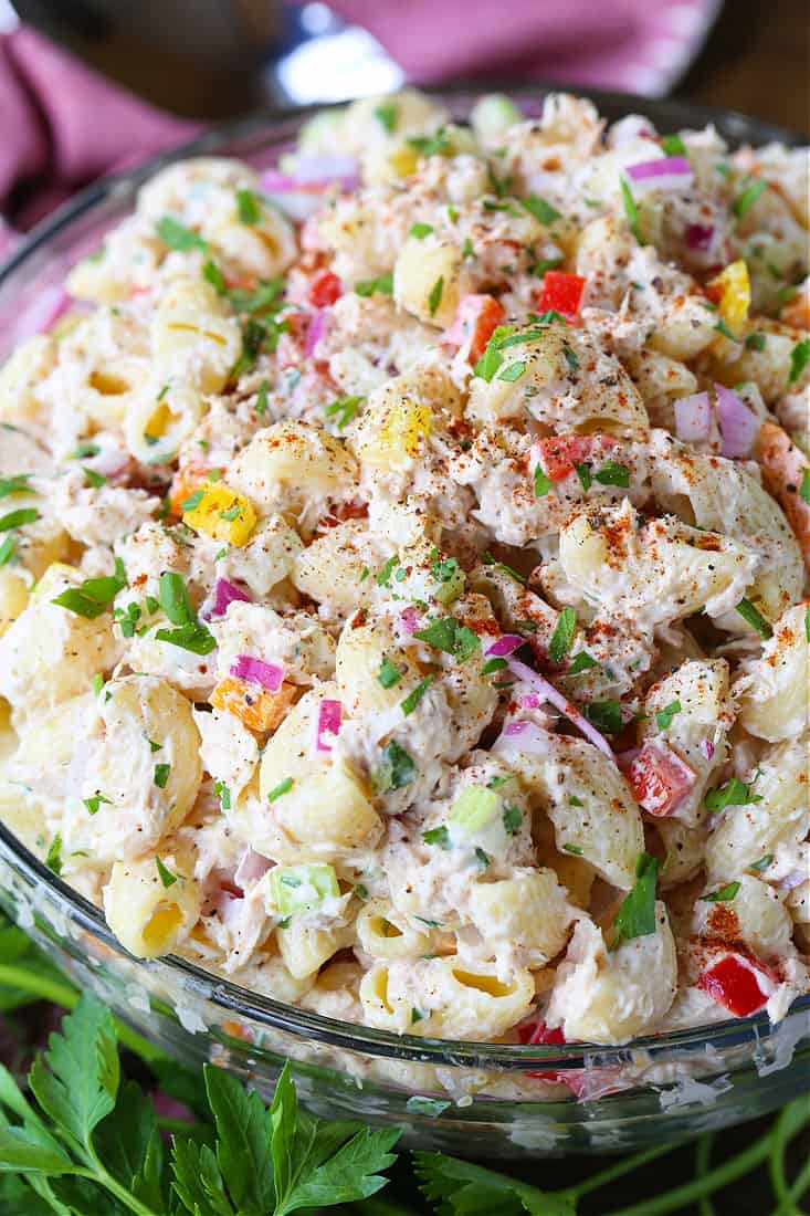 This creamy Tuna Pasta Salad is one of my favorite comfort foods! Perfect for bringing to a BBQ, potluck or for serving at any party! Tuna Pasta Salad recipe in a clear bowl with parsley and napkin