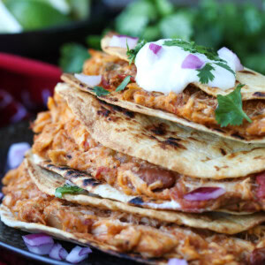 chicken tacos stacked on a plate with sour cream