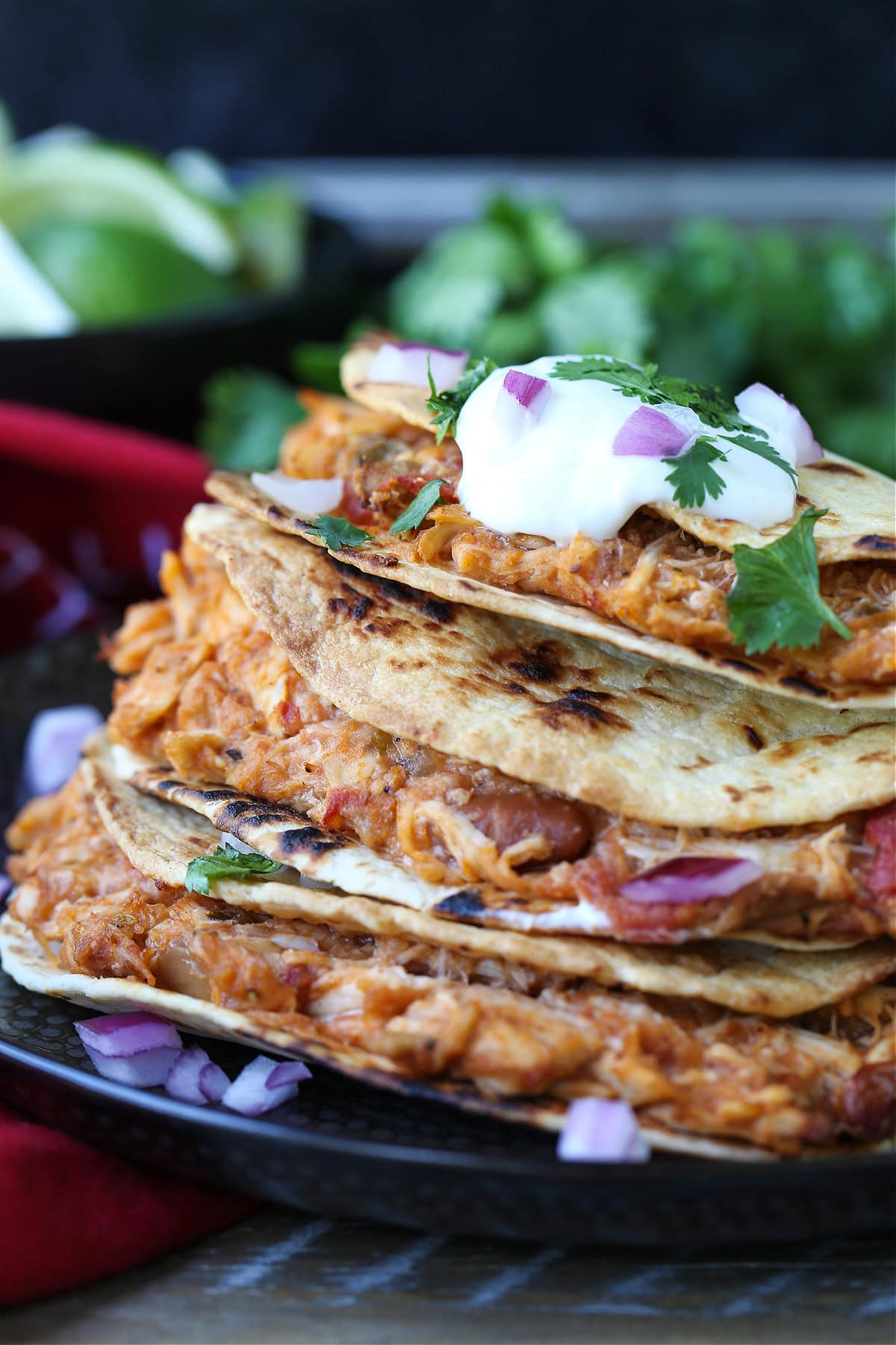 chicken tacos stacked on a plate with sour cream