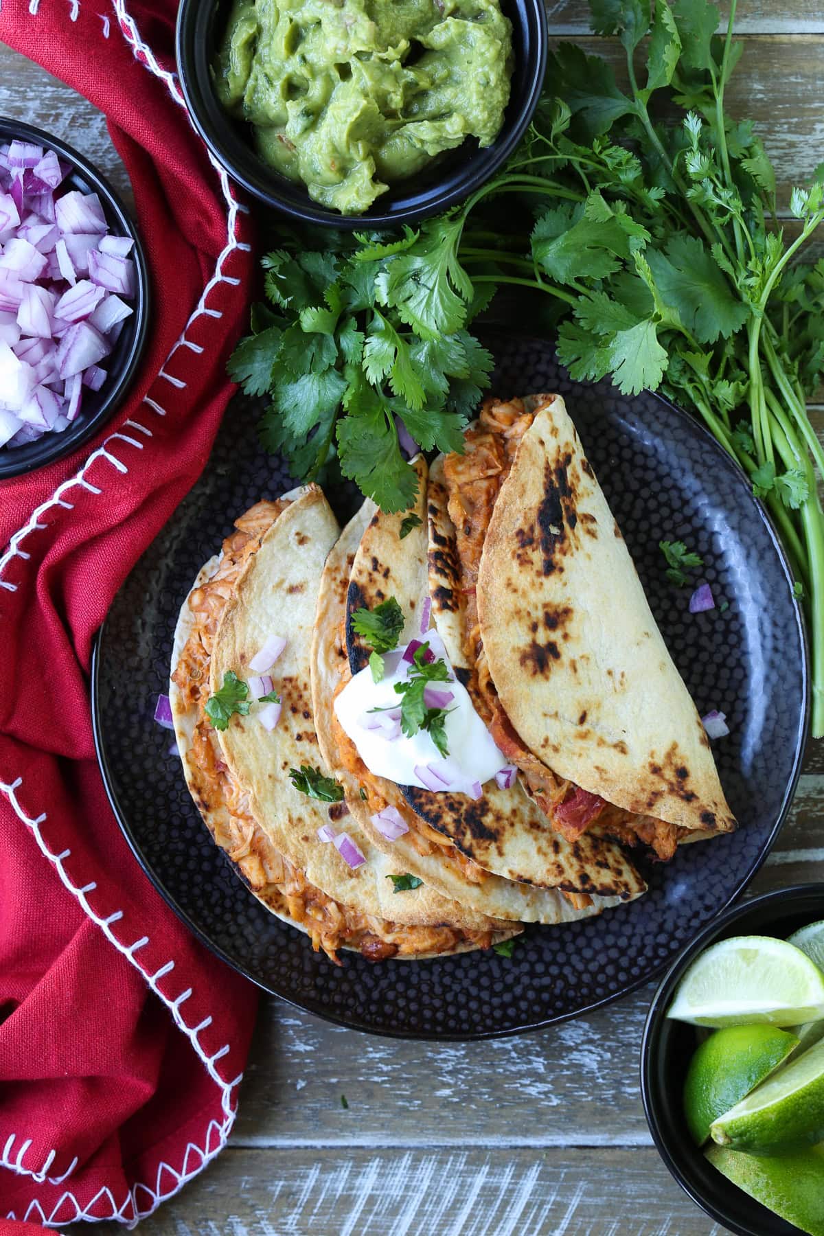 chicken tacos on black plate with toppings and red napkin