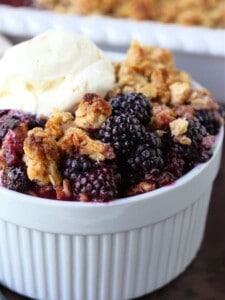 blackberry crisp in a white bowl with ice cream