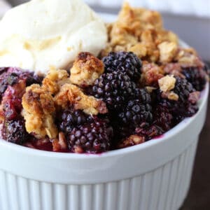 blackberry crisp in a white bowl with ice cream