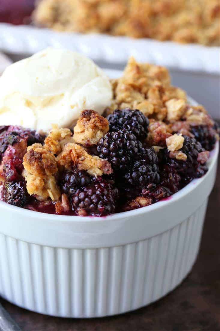 blackberry crisp in a white bowl with ice cream