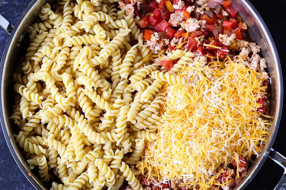 rotini pasta in a skillet with cheese and ground turkey filling