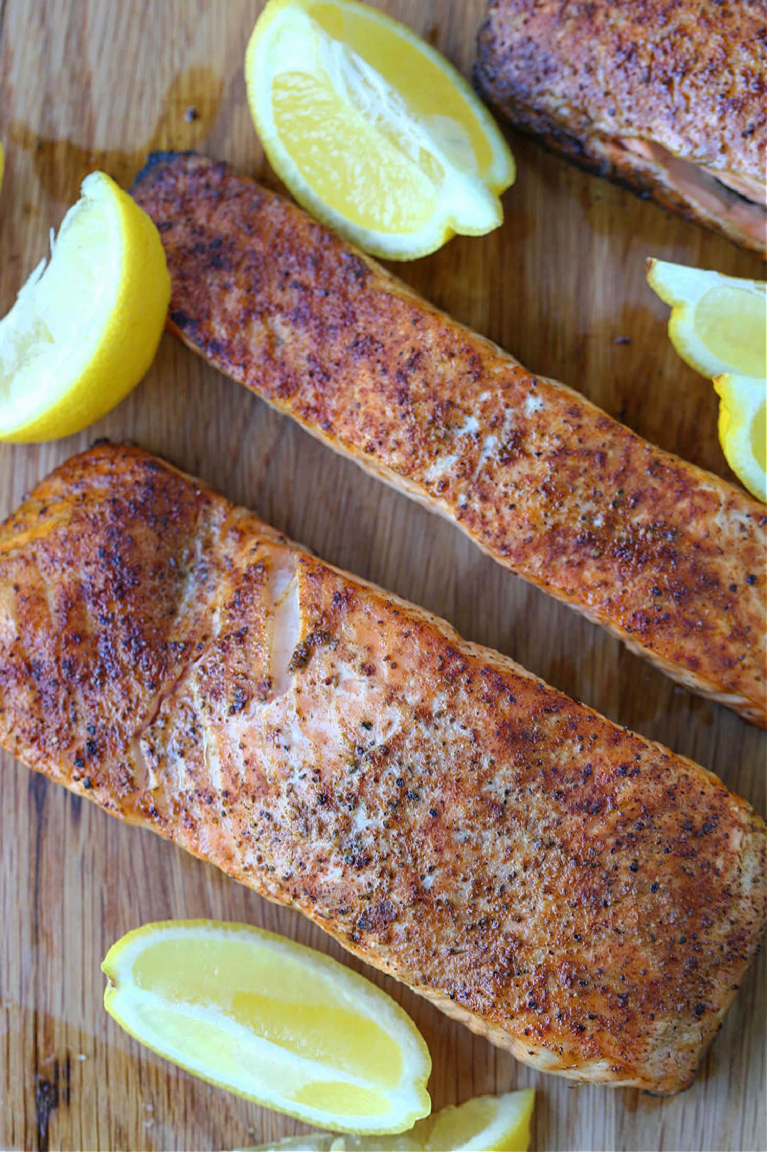 This Easy Grilled Salmon Recipe is the perfect summer dinner! A healthy seafood meal that you can have on the table in 15 minutes! cooked salmon on board with lemons