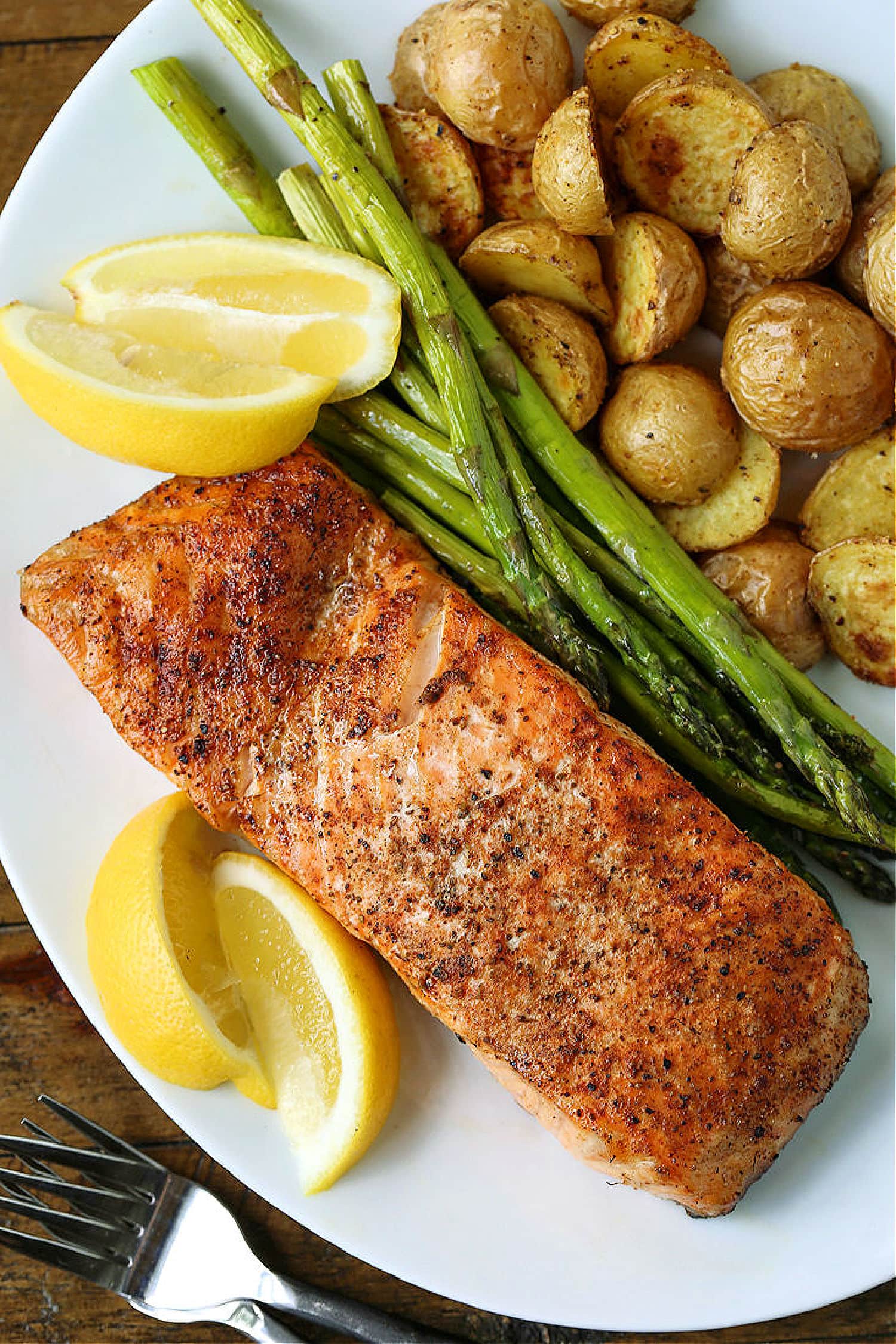 grilled salmon on plate with vegetables and lemons