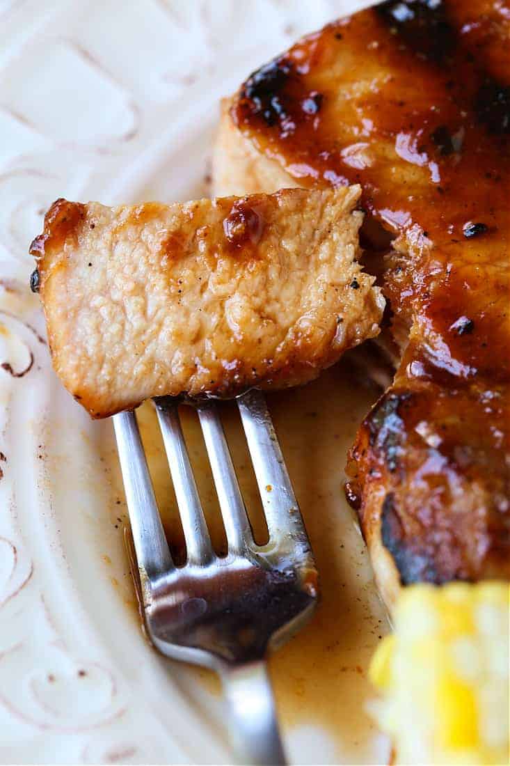 bbq pork chop bite on a fork next to pork chop