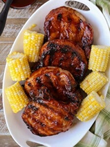 Grilled BBQ pork chops on a platter with corn