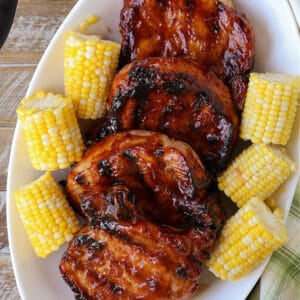Grilled BBQ pork chops on a platter with corn
