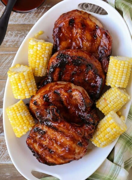 Grilled BBQ pork chops on a platter with corn