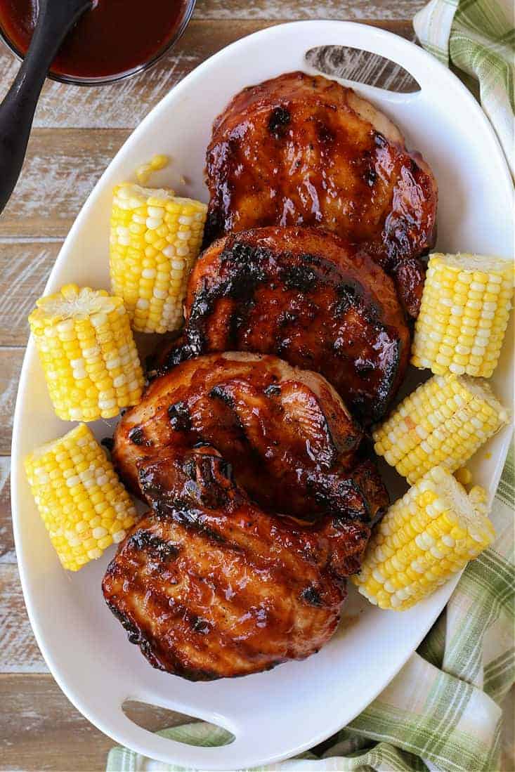 Grilled BBQ pork chops on a platter with corn