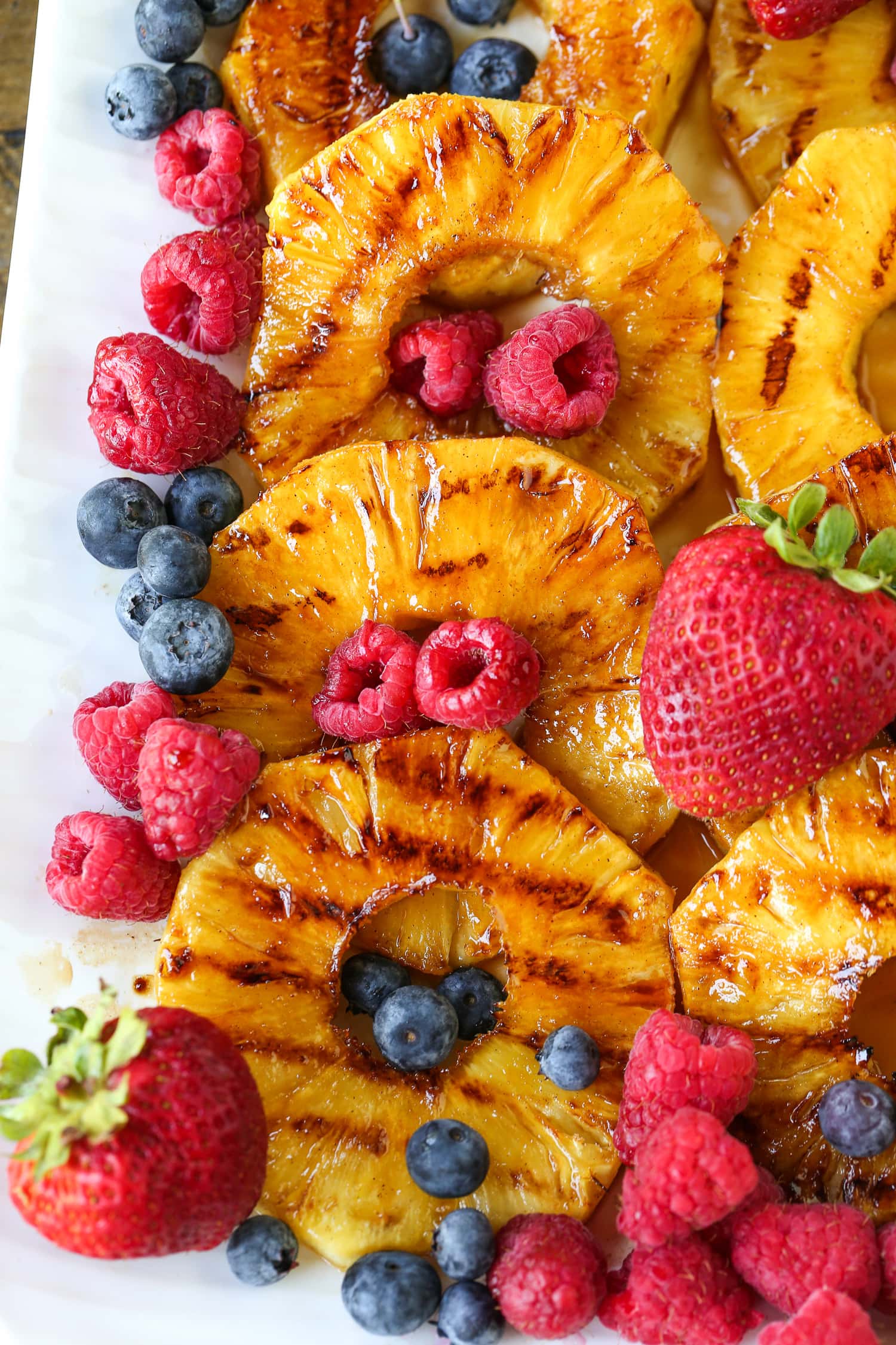 grilled pineapple slices on platter with berries