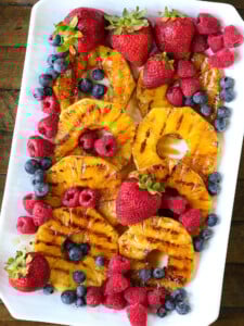 grilled pineapple on a platter with berries