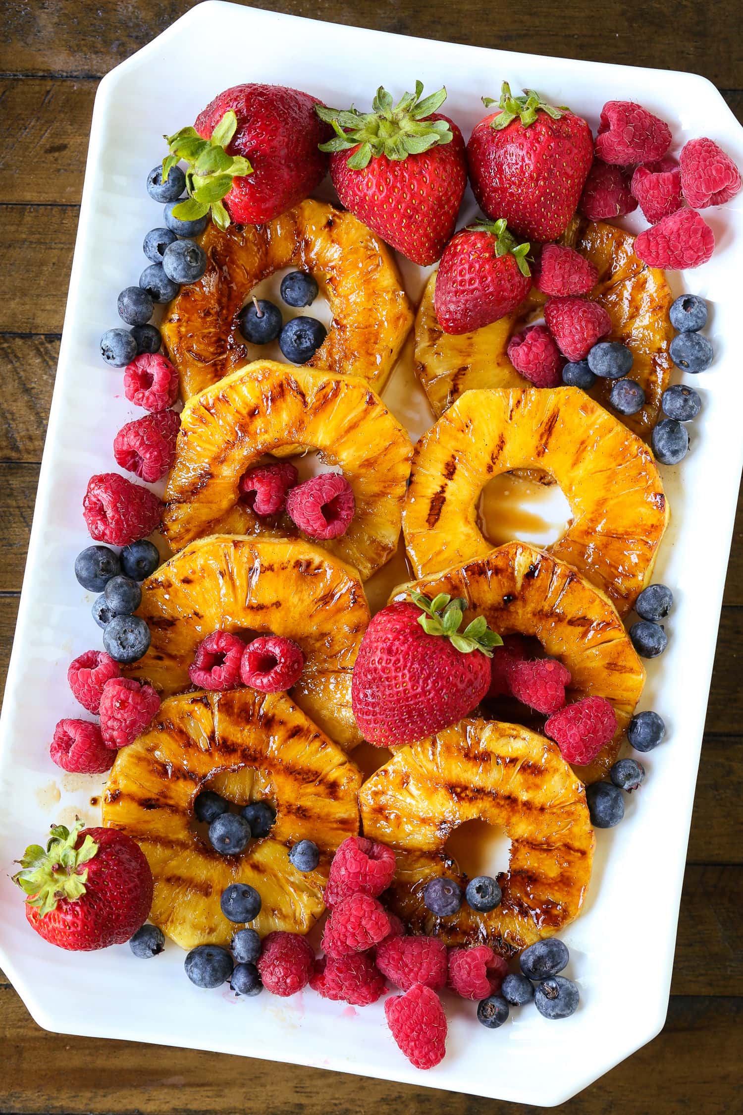 grilled pineapple on a platter with berries