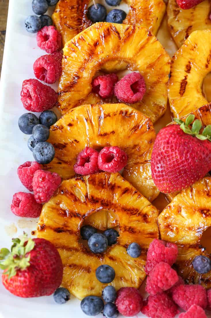 grilled pineapple slices on a platter with fruit