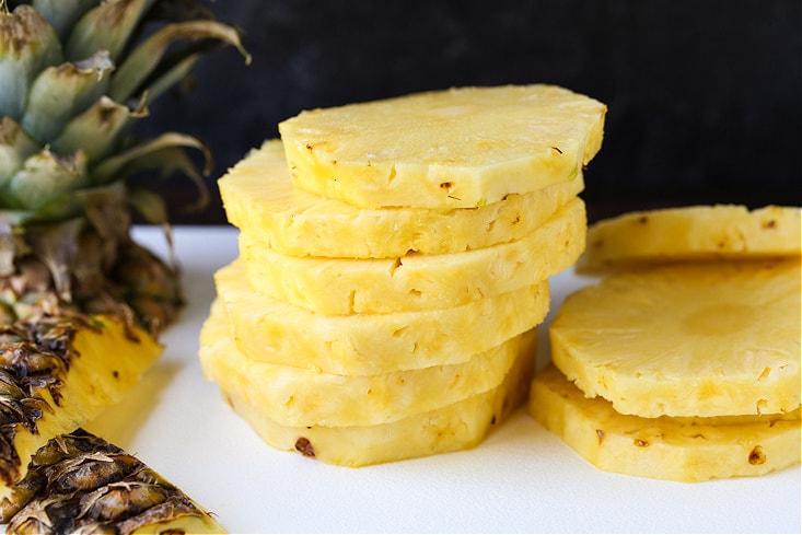 sliced pineapple stacked on a board